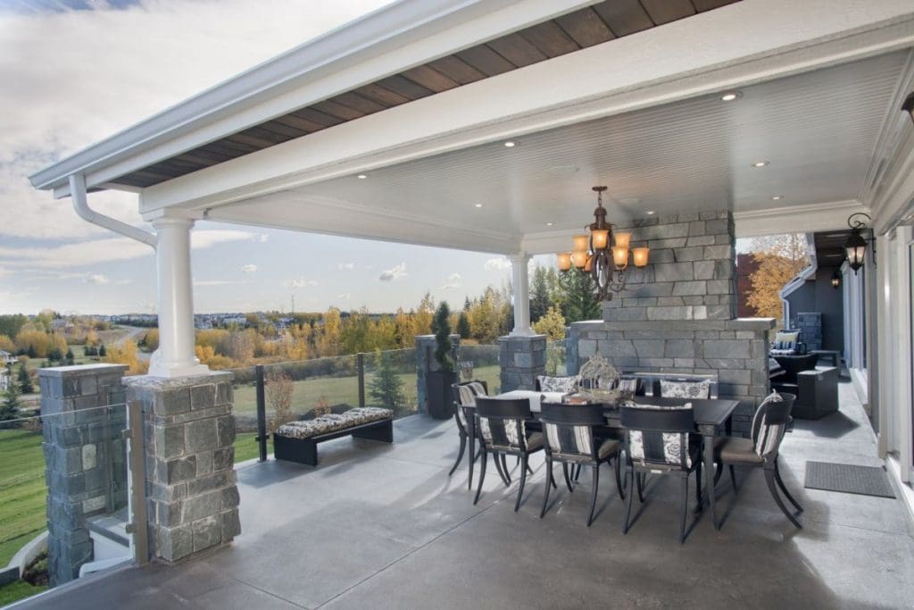 Bearspaw exterior living space with stone fireplace and chandelier above out door table