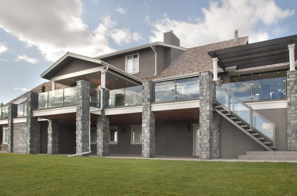 Exterior of Bearspaw exterior renovation with stoned pillars and glass railings