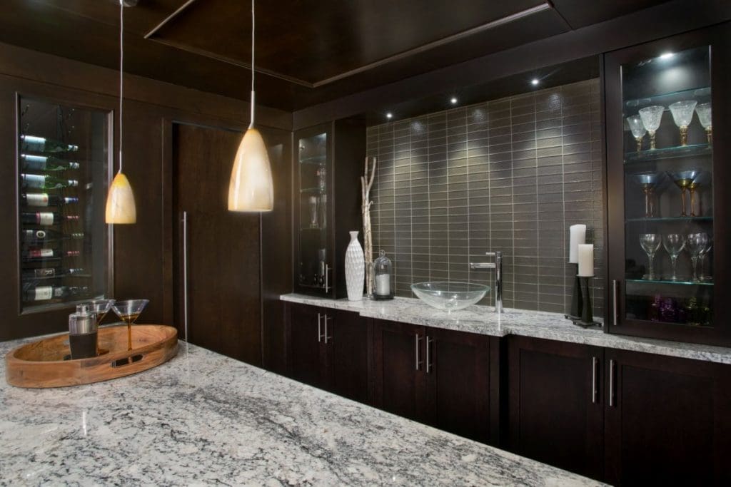 Hamptons renovations by renova homes and renovations basement wet bar with deep mahogany cabinets and tiling throughout