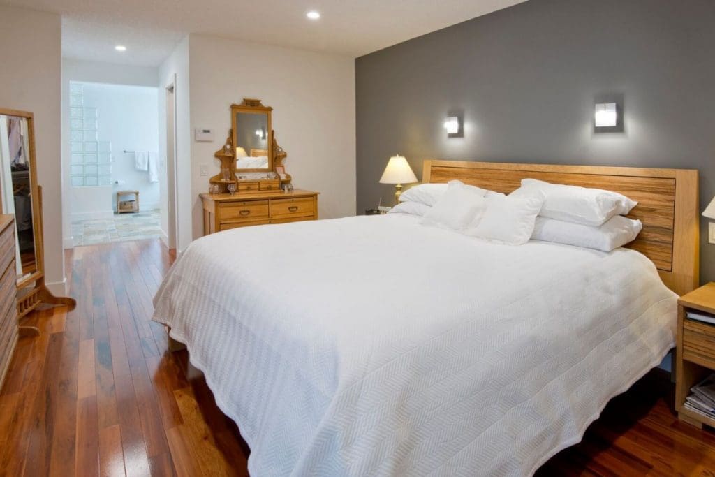 Hawkwood Renovation By Renova Homes & Renovations Calgary, Alberta master bedroom with a grey accent wall leading into the vanity and bull bath