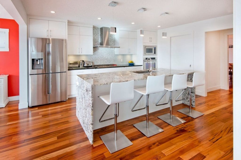Hawkwood home with custom full marble island with red wood hardwood and white cabinets