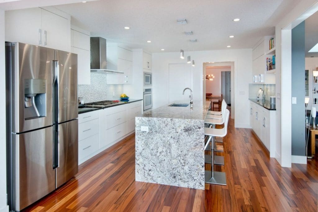 Hawkwood home with custom full marble island with red wood hardwood and white cabinets