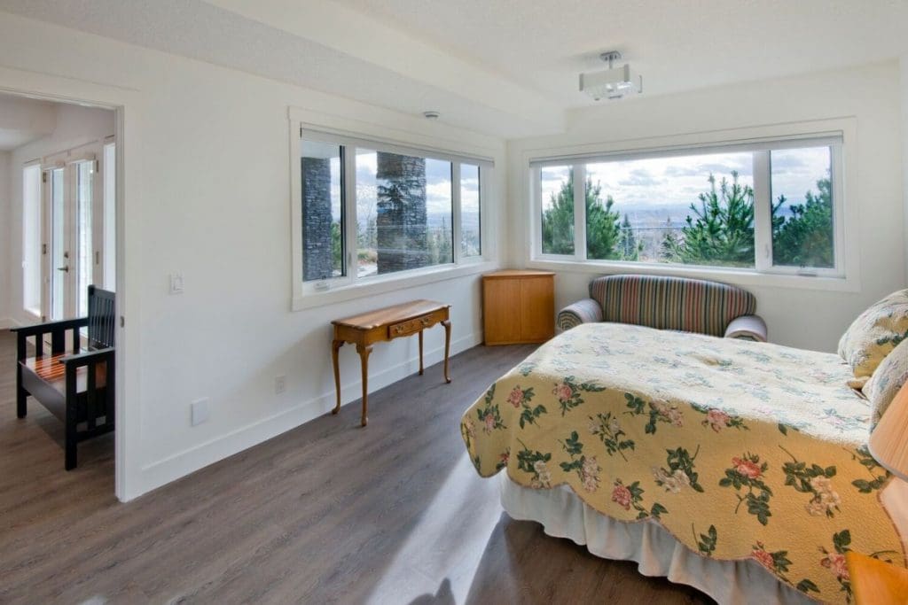 Hawkwood Renovation By Renova Homes & Renovations Calgary, Alberta master bedroom with corner windows overlooking the valley