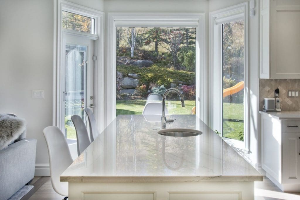 Patterson Interior Project By Renova Homes & Renovations Calgary, Alberta kitchen island leading into floor to ceiling windows showcasing the Lucious back yard