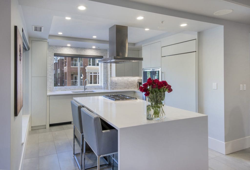 Princeton Renovation of kitchen with large quartz island with stove and stainless steel hood vent fan