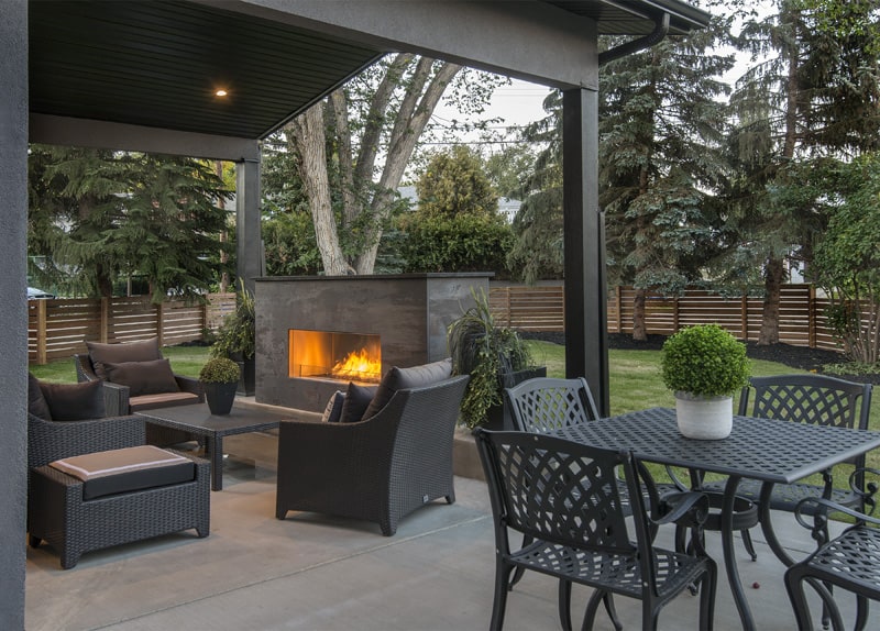 Renova Feature Home 2018 By Renova Homes & Renovations Calgary, Alberta exterior backyard with landscaping and greenery surrounding the stone firepit